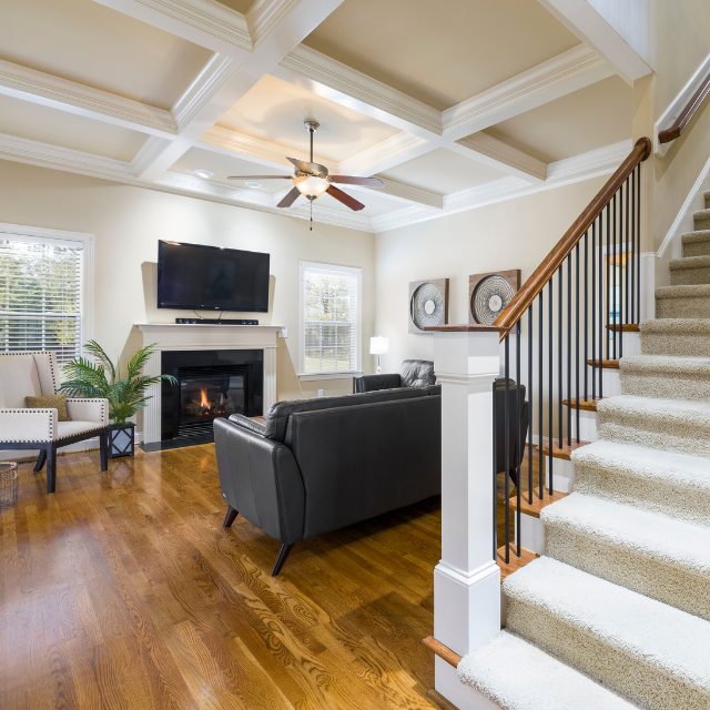 Modern basement space featuring a fireplace, overhead ceiling fan, and window that fills the room with natural light.