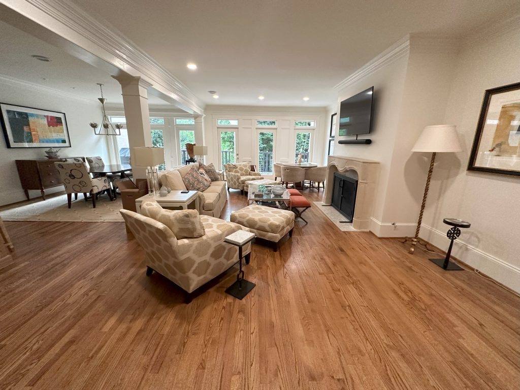 View of a newly renovated living space connecting to the dining room and kitchen area, showcasing new flooring and lighting in an Alpharetta home.