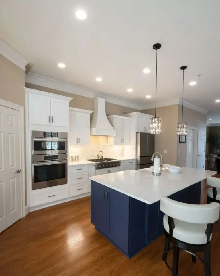 Open layout kitchen remodel in Alpharetta, GA with white cabinets, quartz countertops, and navy island with seating