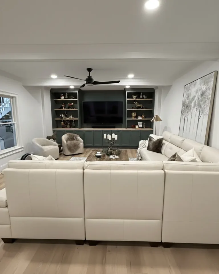 Luxury basement home remodeling project with custom built-in entertainment center, sectional seating, and modern interior finishes.