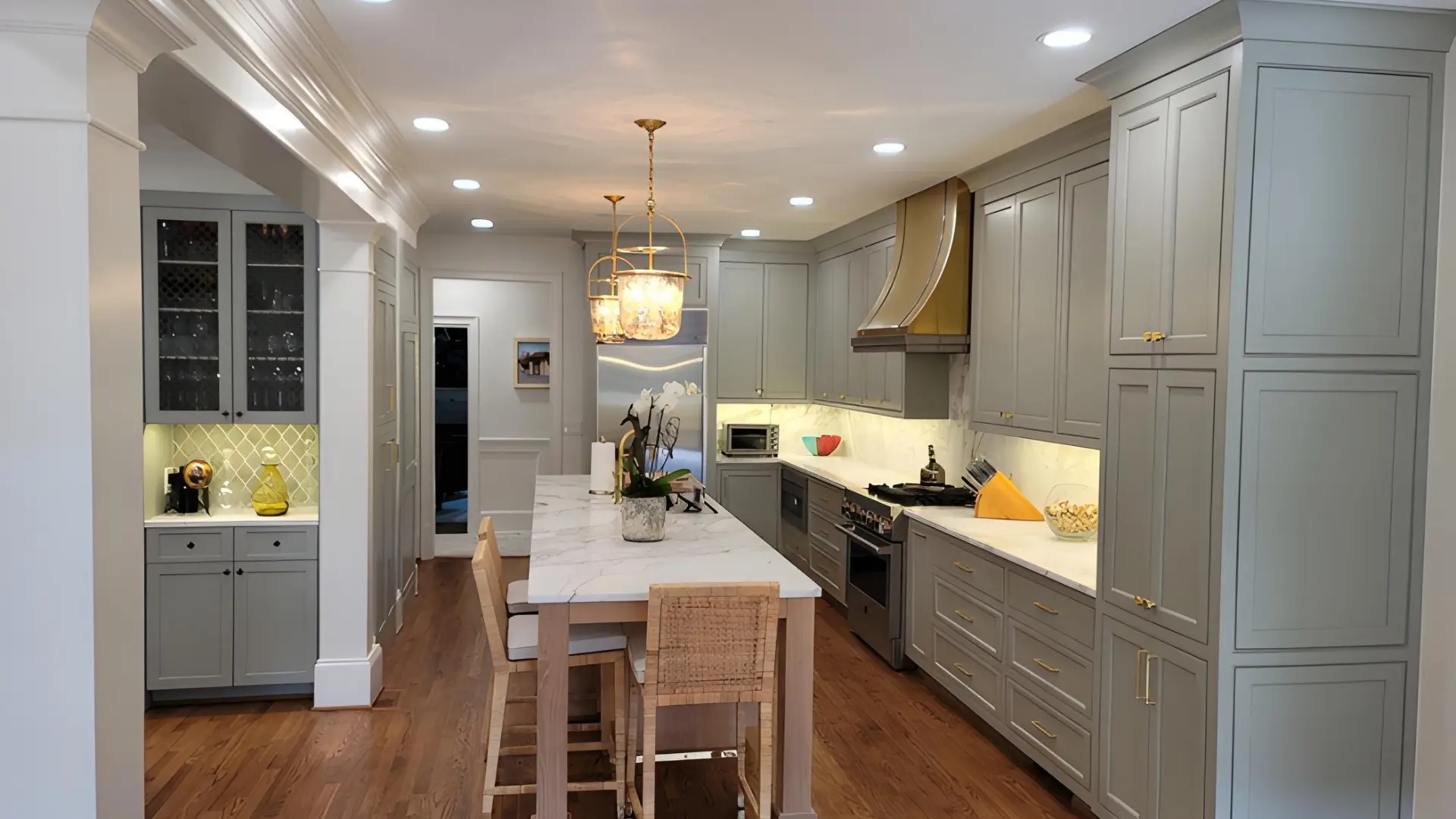 Luxury kitchen remodel in Alpharetta, GA featuring custom gray cabinetry, marble countertops, hardwood floors, and large center island.