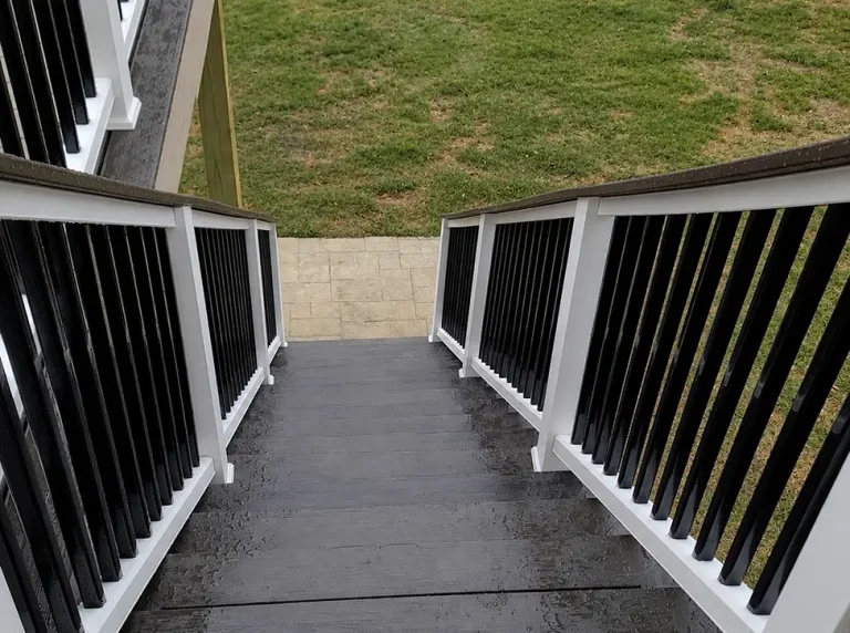 TimberTech composite deck staircase with matte white railing and black aluminum balusters leading to a covered outdoor living patio.