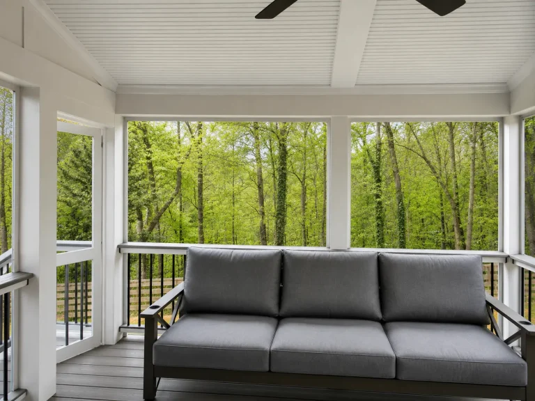 Interior of a completed premium screened porch with composite decking overlooking a wooded backyard in North Atlanta by Yanover Construction.
