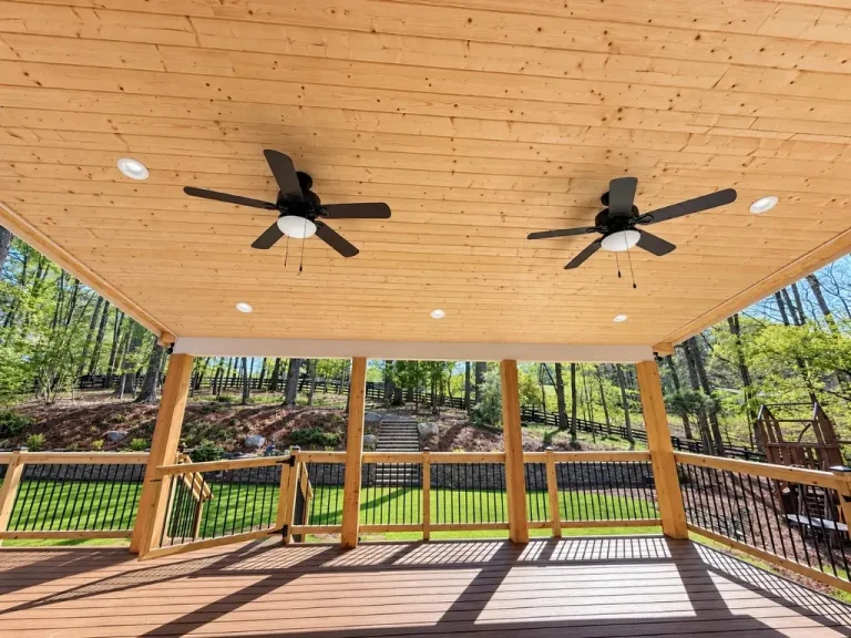Covered porch with tongue-and-groove pine ceiling, two black ceiling fans, Trex composite decking, and wood railing in Alpharetta, GA.