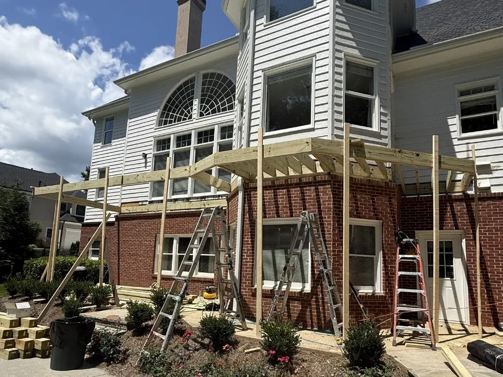 Structural deck framing under construction with pressure-treated lumber, support posts, and beams at a North Atlanta home.