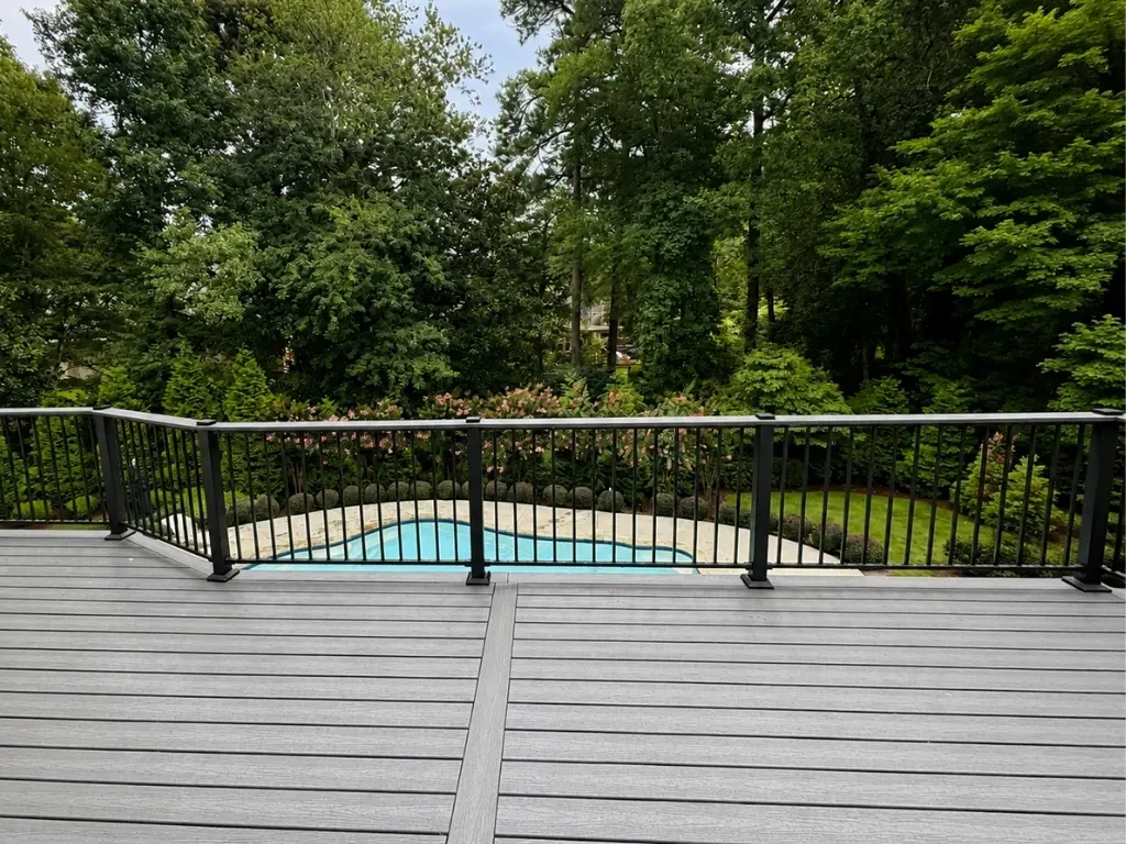 Exterior remodeling project featuring a custom composite deck with black railing overlooking a backyard pool in North Atlanta