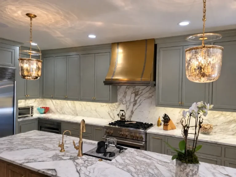 Buckhead kitchen remodel with gray cabinets, stone backsplash, statement range hood, and pendant lighting.