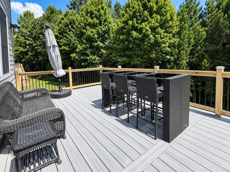 Trex composite deck in Cumming, GA with gray decking, wood railings, black aluminum balusters, and outdoor seating.