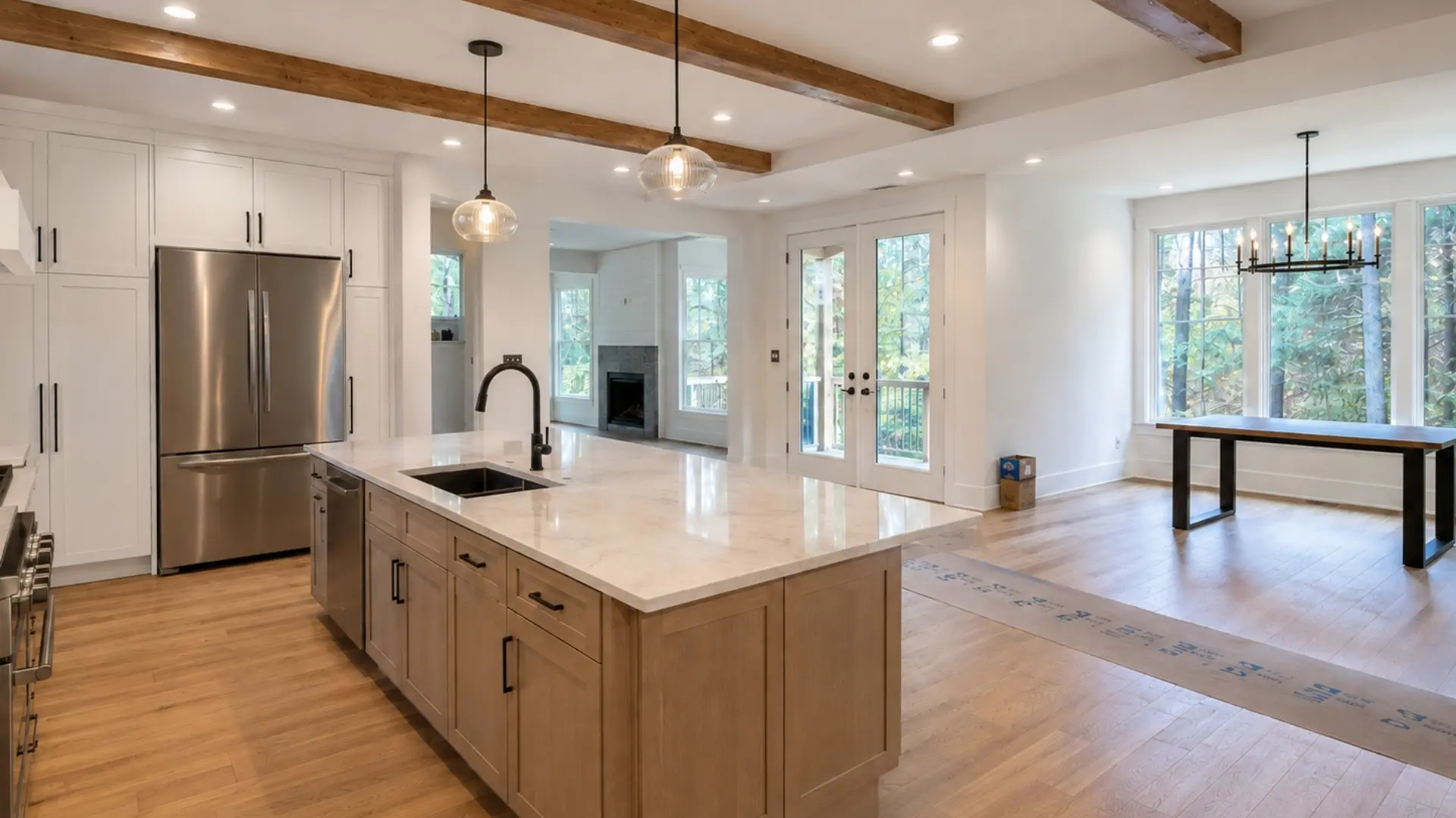 Open-concept renovated kitchen and living area with white cabinetry, wood island, exposed ceiling beams, and hardwood floors in North Atlanta.