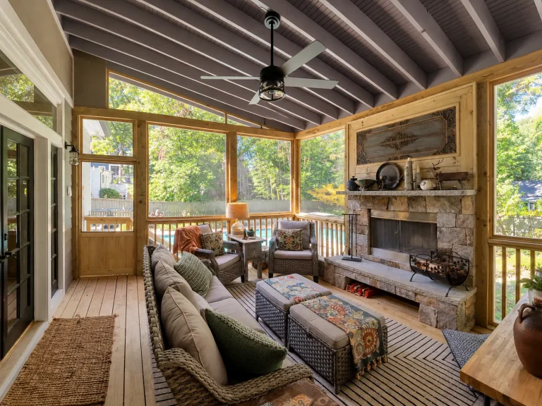 Spacious screened porch interior featuring a fireplace and exposed ceiling details.