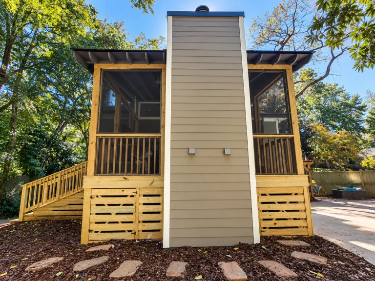 Exterior view of a custom elevated screened porch featuring a covered deck and fireplace.